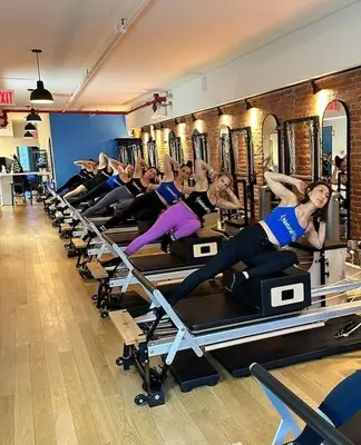 Nicole G’s 5-star review shown with a group Pilates reformer class at Natural Pilates studio.