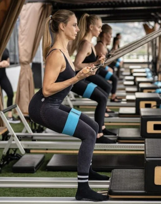Woman exercising on Pilates reformer machine with testimonial review saying “Over 1,000 5-star reviews.”